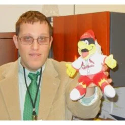 Man with glasses in suit and tie holding a puppet of St. Louis Cardinals baseball mascot Fredbird